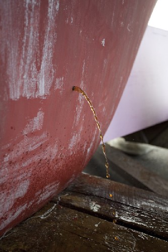 Water pours out from the hole drilled into the keel